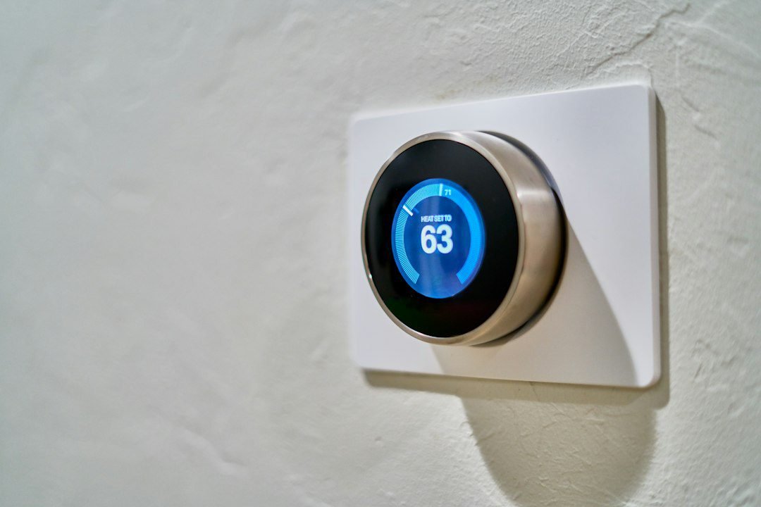 Termostato digital circular instalado en una pared.